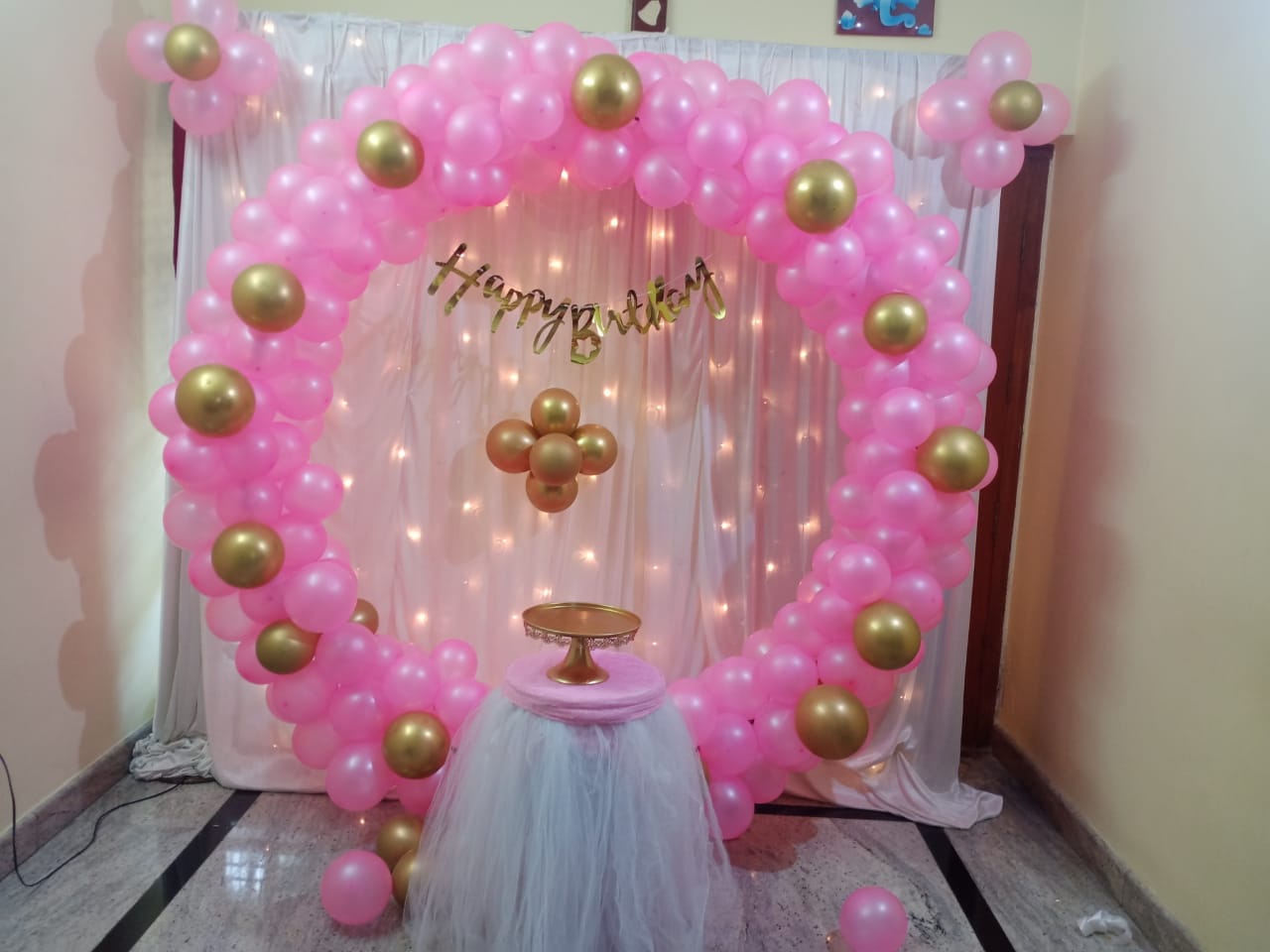 Pink & Gold Halo — A balloon ring on sheer drapes with fairy lights for an intimate birthday.