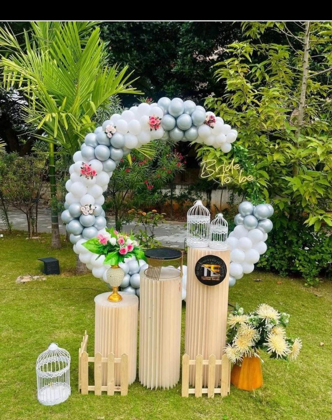 Garden Ring Welcome — A sage-and-white balloon ring with birdcages and picket detail in a garden lawn.