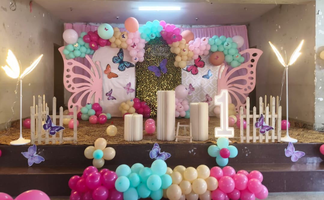 Butterfly Meadow — A soft pink butterfly backdrop with candle pillars and a picket-fence base.