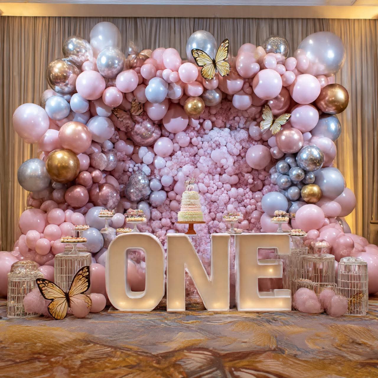One in Rose Gold — A rose-gold balloon wall and marquee letters for a first birthday.
