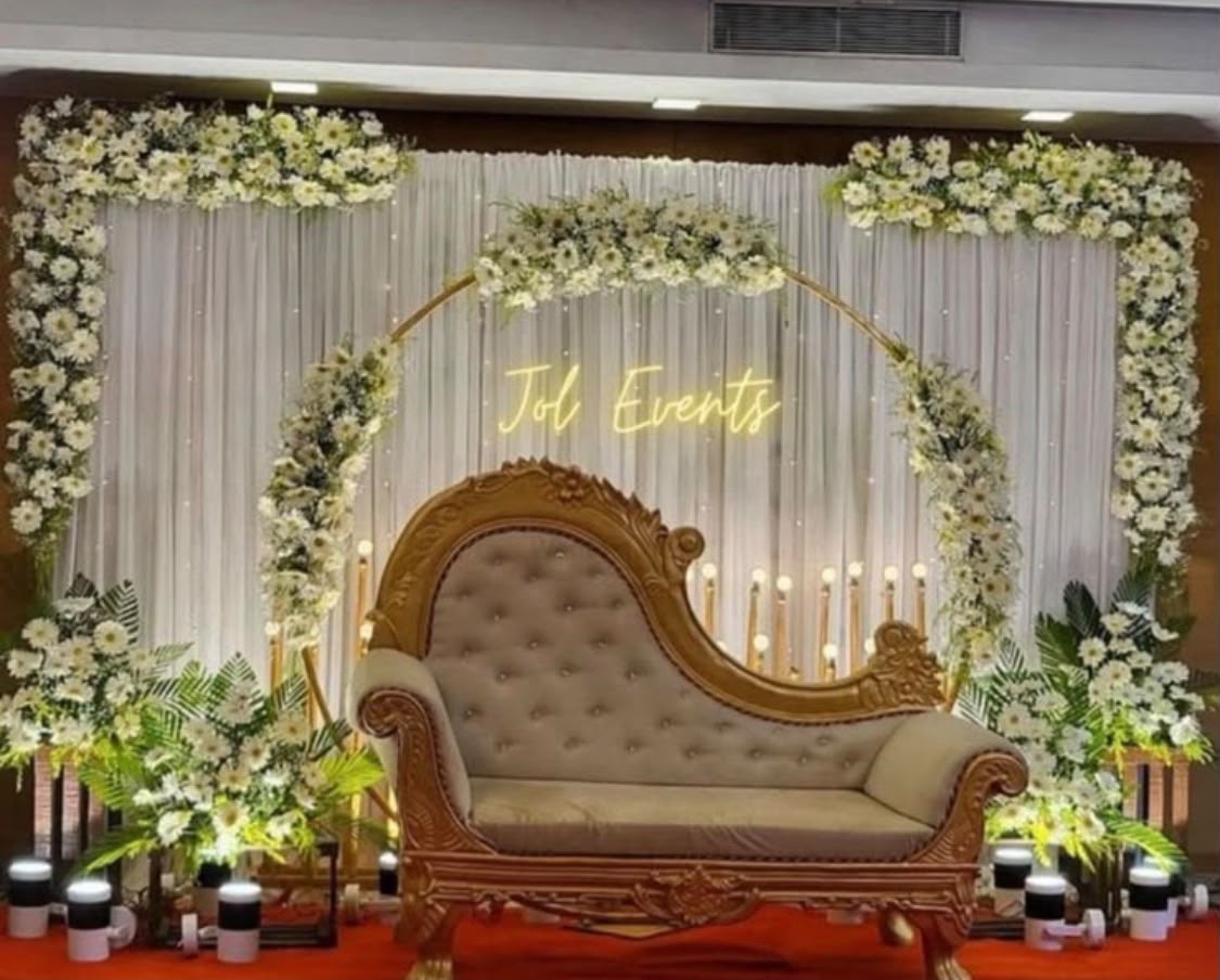 The Golden Arch — A floral ring backdrop with a carved chaise for an engagement evening.